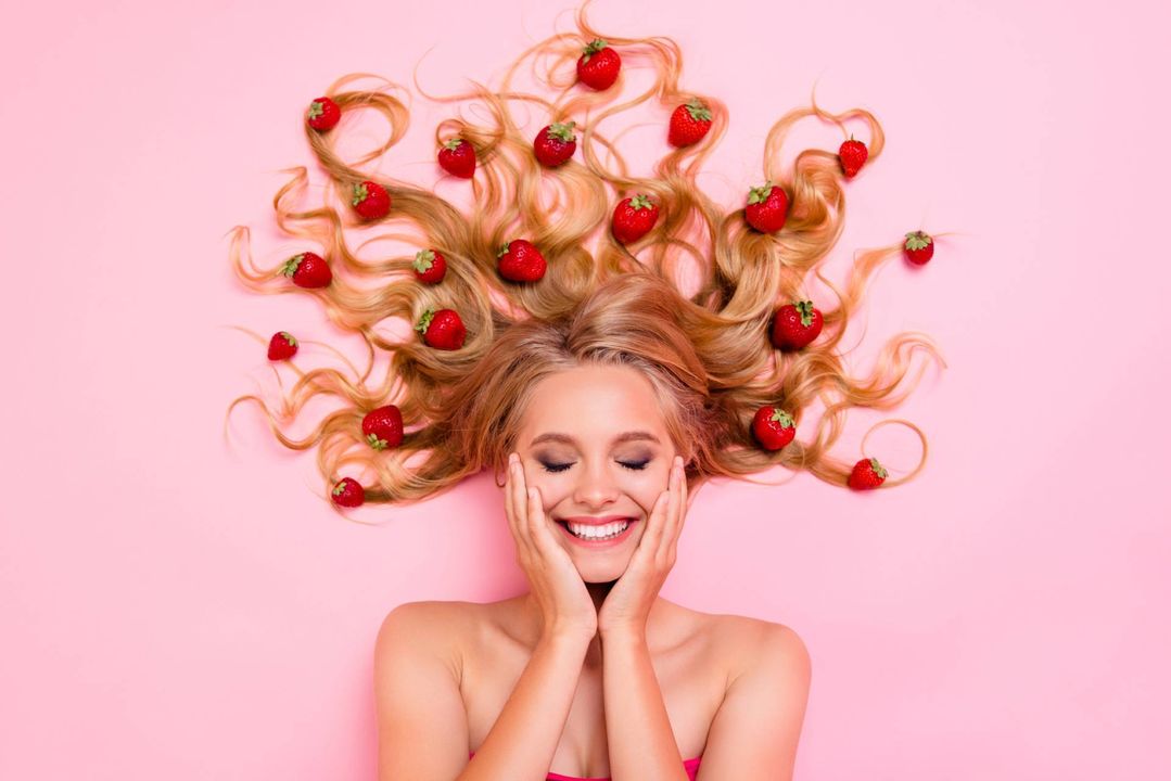 Frau am lächeln mit Erdbeeren auf der Haare