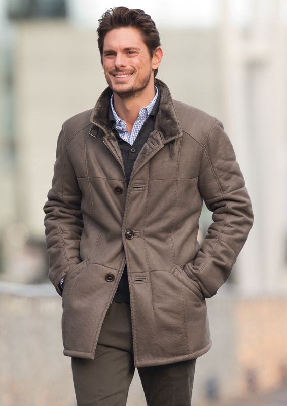 Ein Mann trägt einen braunen Mantel und lächelt