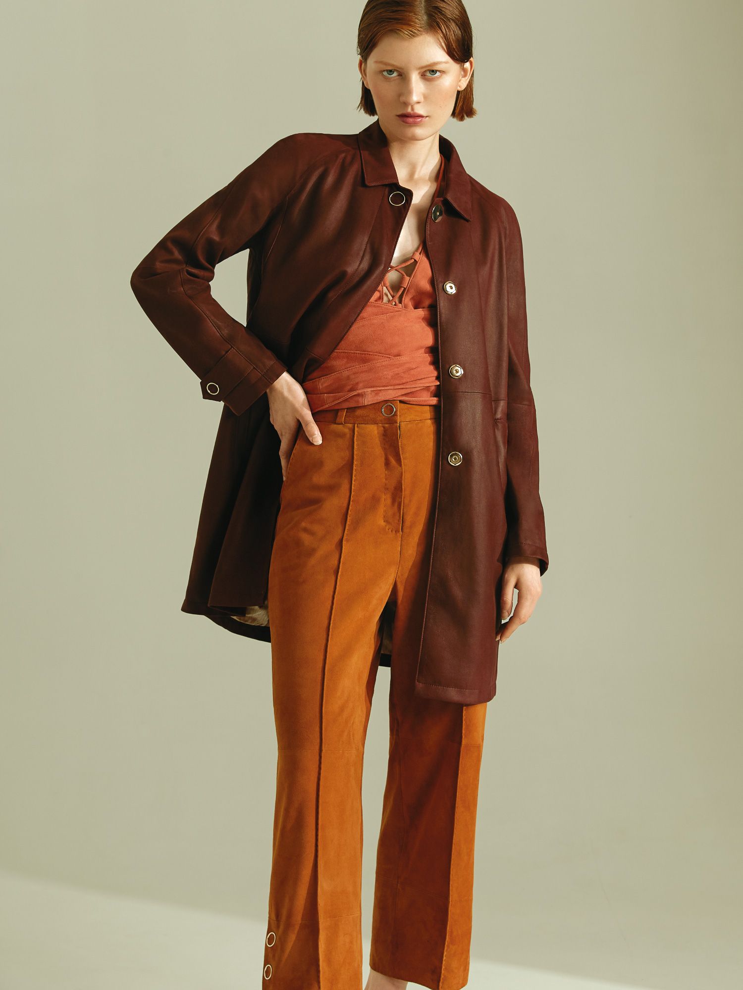 Eine Frau trägt einen braunen Mantel und orangefarbene Hosen.
