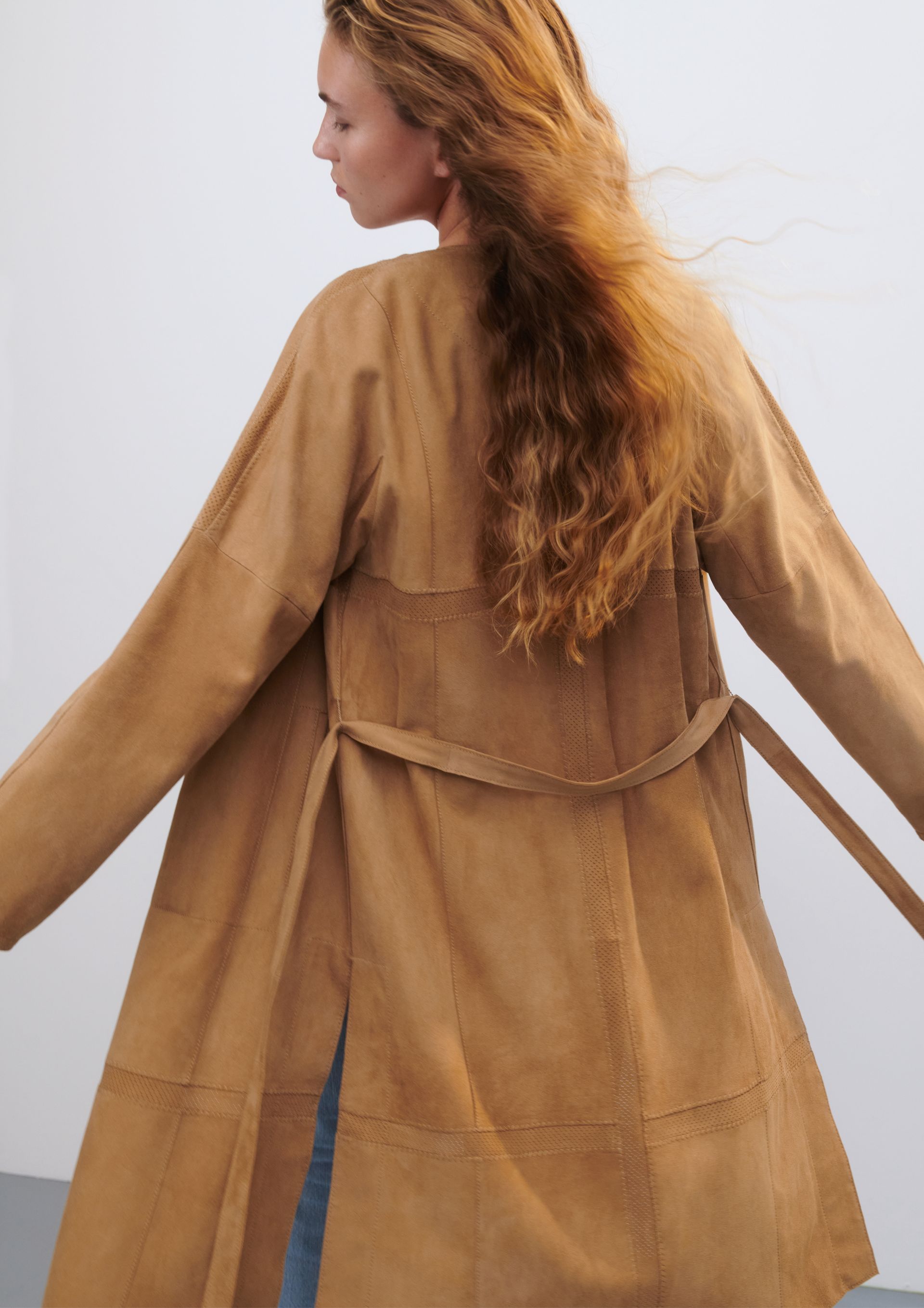 Der Rücken einer Frau in einem braunen Mantel