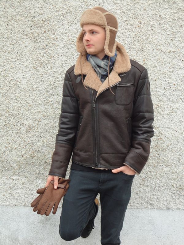 Ein Mann mit Hut und Jacke hält ein Paar Handschuhe