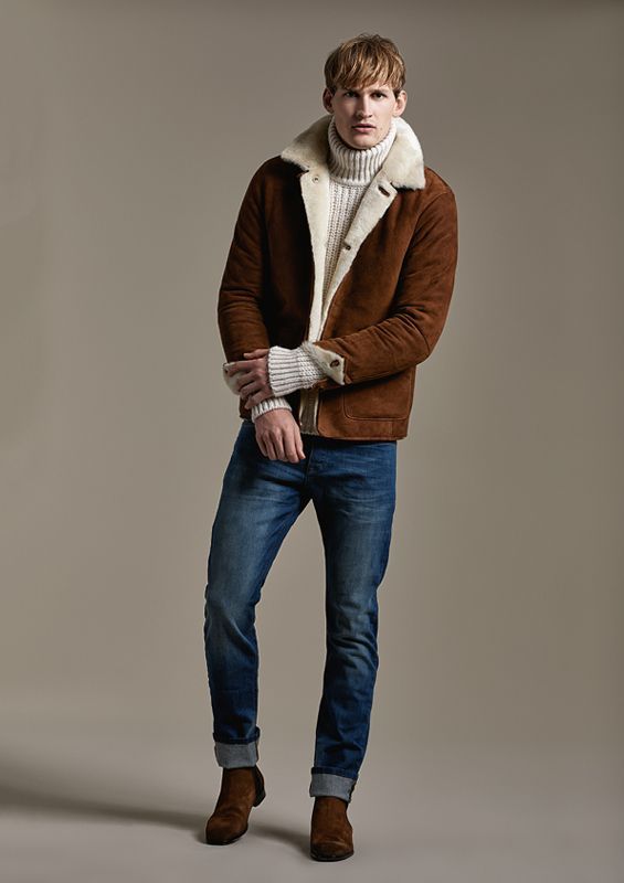 Ein Mann trägt eine braune Jacke und einen Rollkragenpullover.