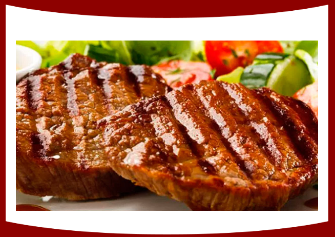 Un primer plano de un filete a la parrilla en un plato con verduras.