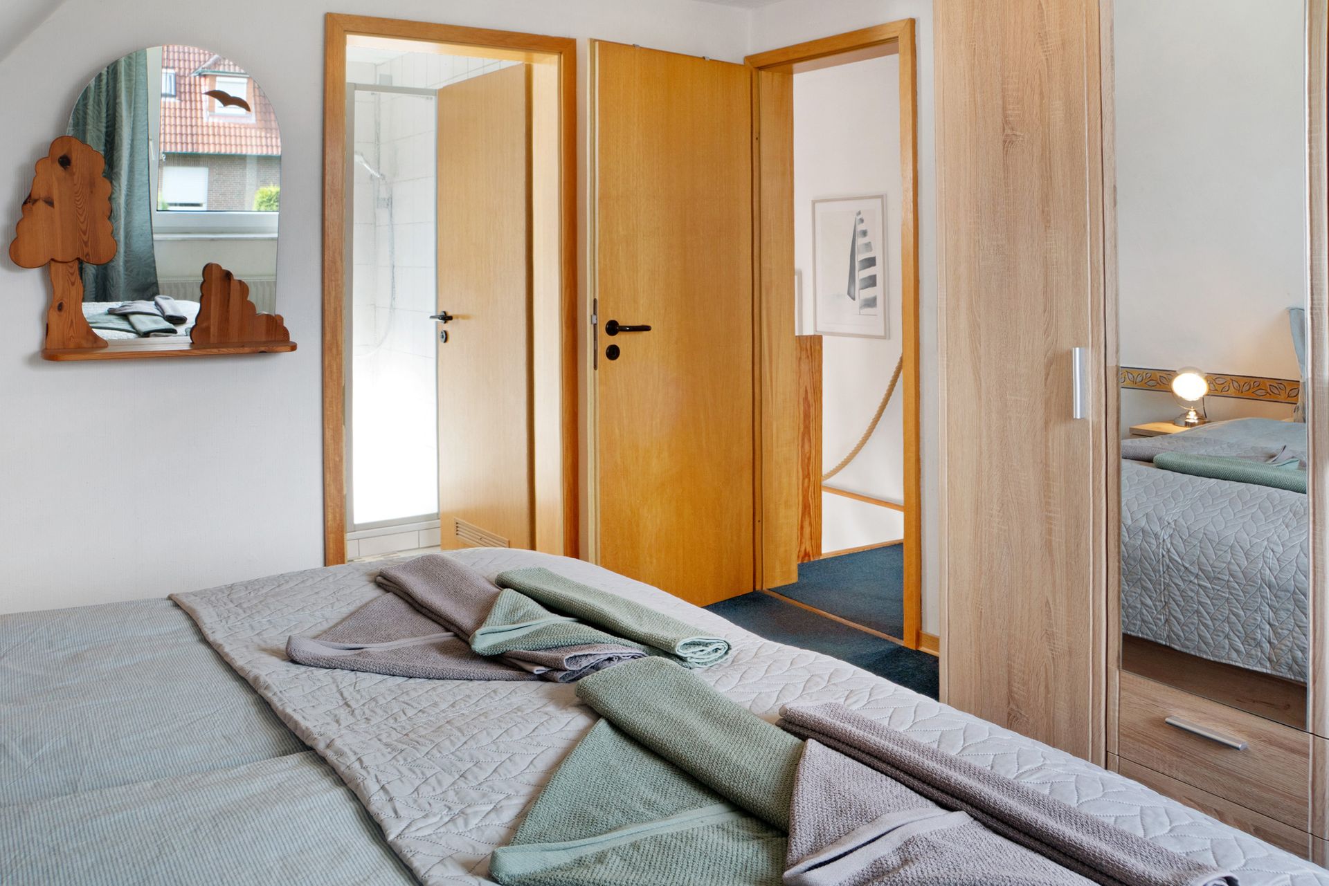 Schlafzimmerinterieur mit Bett, Holztüren, Spiegel mit einzigartigem Rahmen und Kleiderschrank.