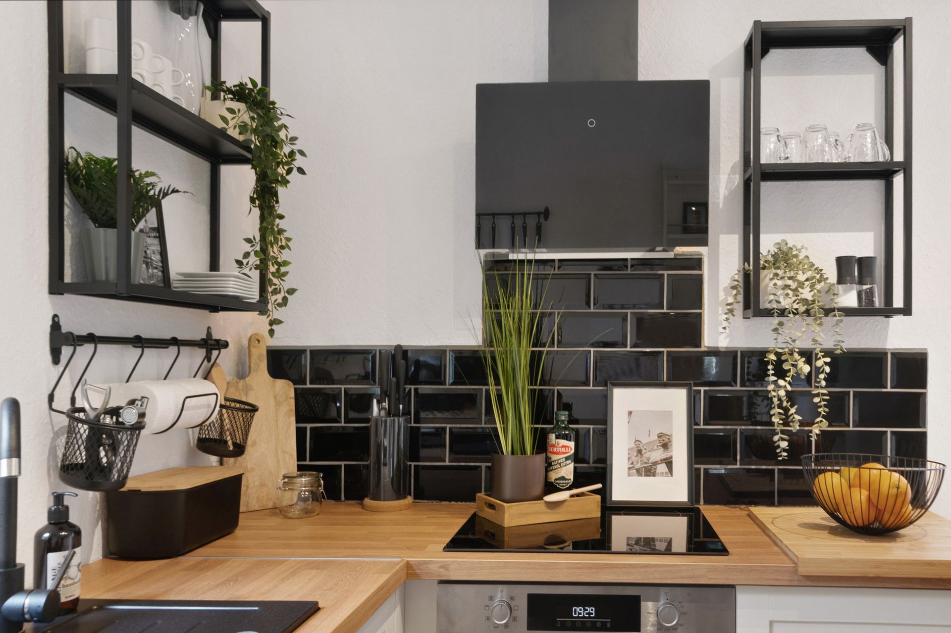 Moderne Küche mit schwarzen Akzenten. Schwarzer Fliesenspiegel, offene Regale, Arbeitsplatten aus Holz.