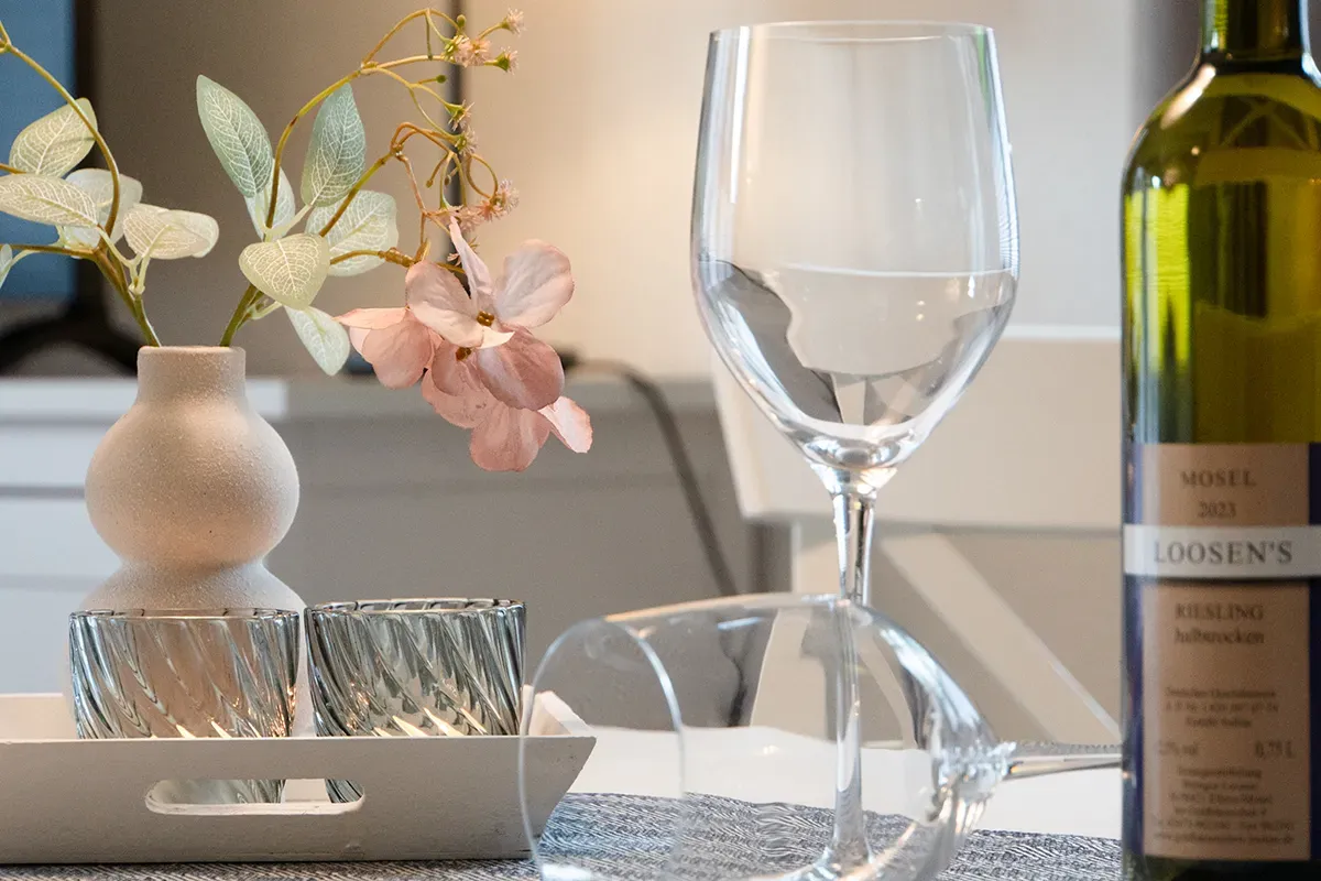 Weingläser und Flasche auf dem Tisch mit Blumenarrangement.