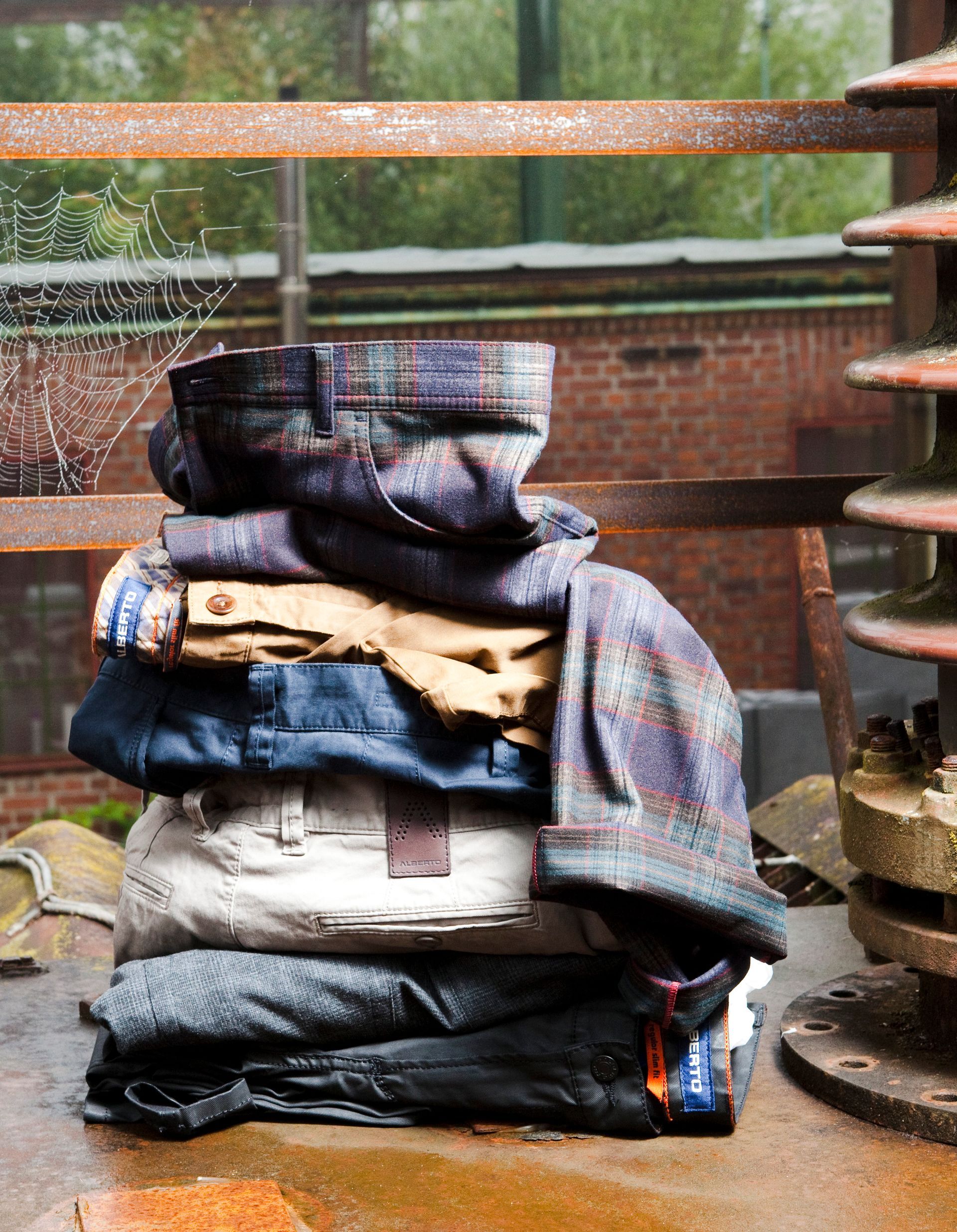 Fashion-Fotografie - Vor einem Backsteingebäude liegt ein Haufen Kleidung auf dem Boden.
