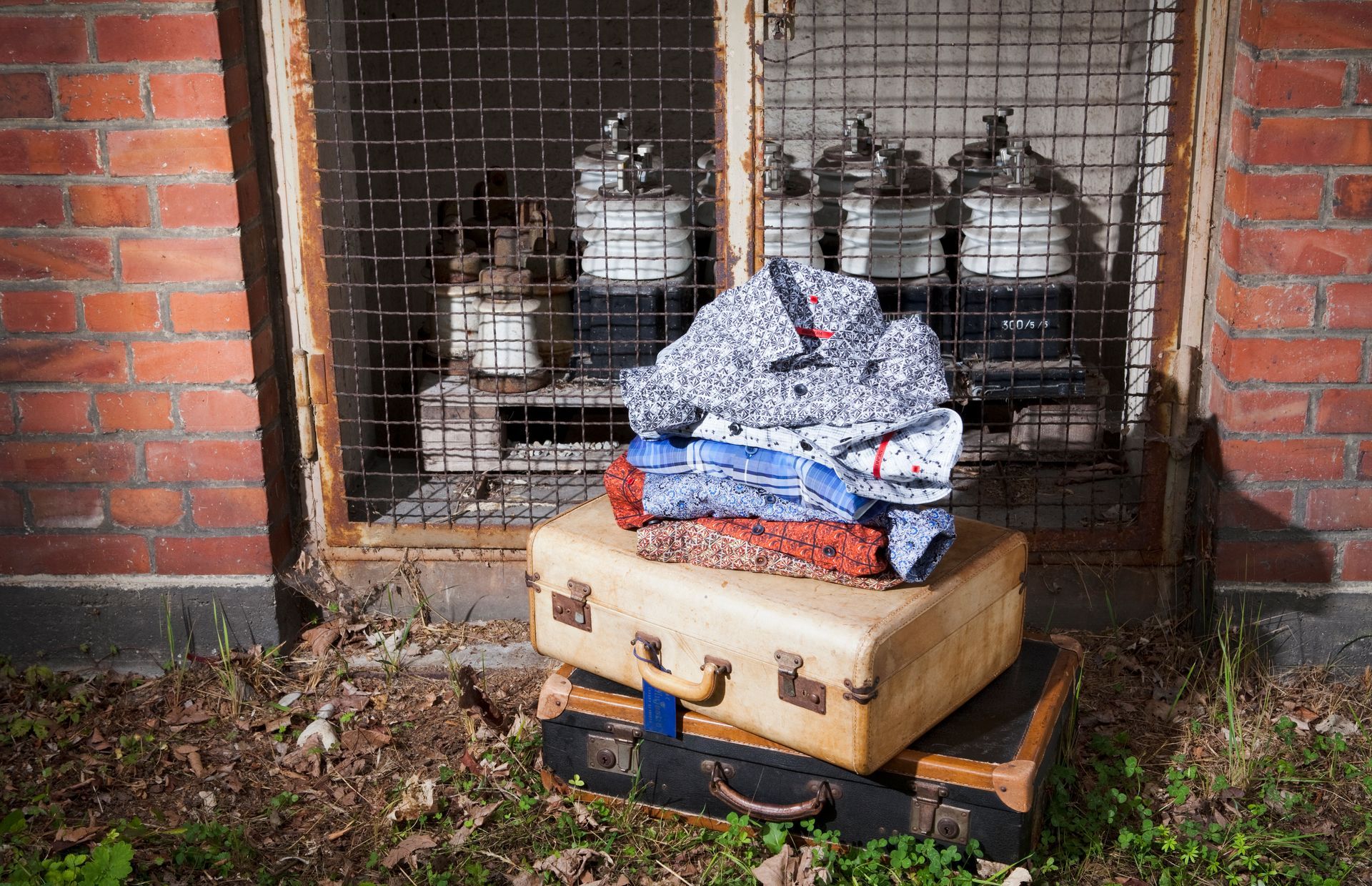 Fashion- Fotografie- Ein Stapel Koffer vor einer Backsteinmauer