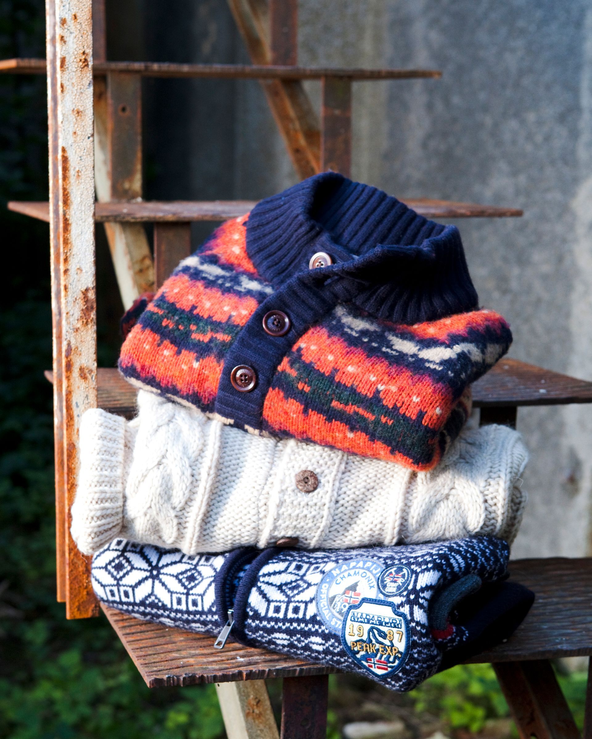 Fashion-Fotografie - Drei Pullover sind übereinander auf einer Leiter gestapelt