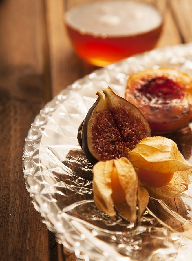 Food - Fotografie - Ein Glasteller mit Feigen und Physalis auf einem Holztisch.