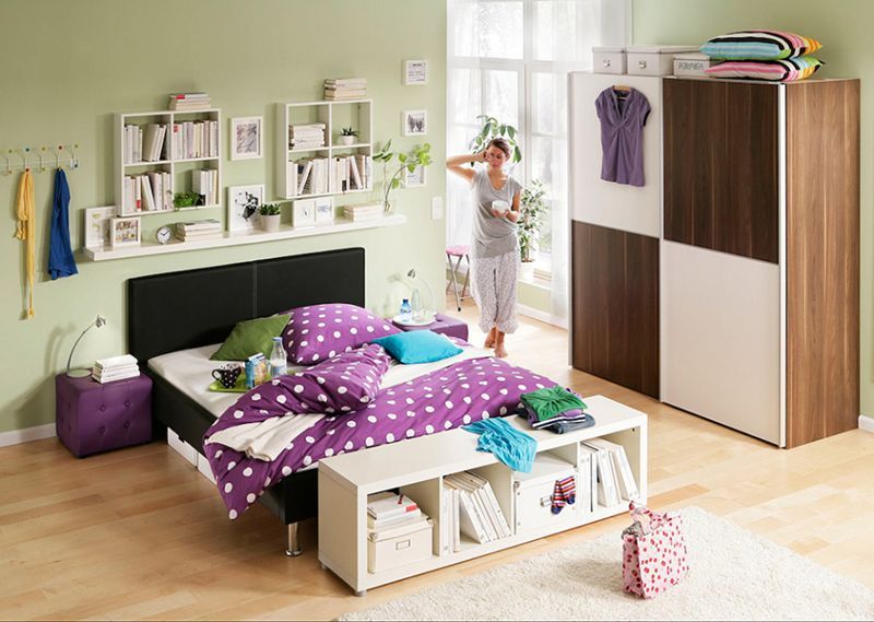 Eine Frau steht neben einem Bett in einem Schlafzimmer