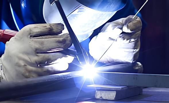 Behandschuhte Hände verschweißen Metall mit einem hellblau-weißen Lichtbogen