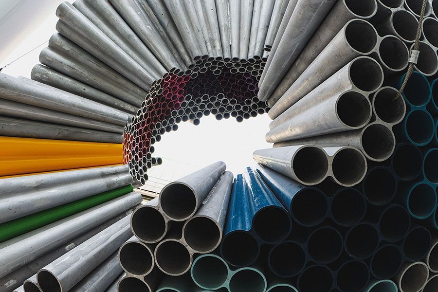 Stapel von Metallrohren, kreisförmig angeordnet, mit grauen, schwarzen, blauen und orangen Abschnitten