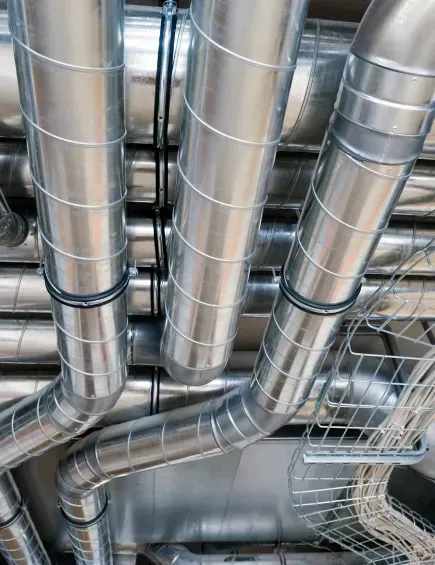 Silberne industrielle Lüftungskanäle und -rohre an einer Decke mit Metallrahmen.