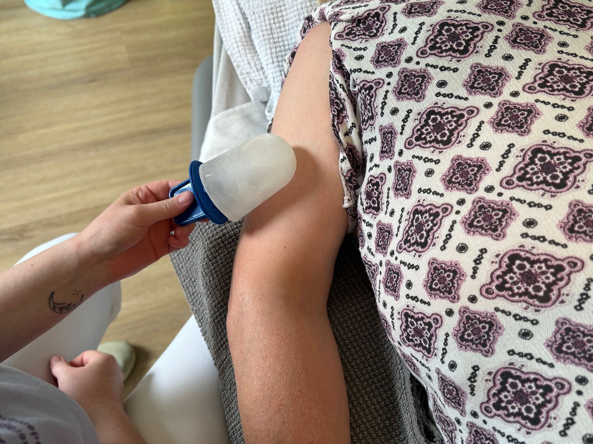 Person erhält Eistherapie am Arm. Eine Hand hält einen Eisbeutel-Applikator.