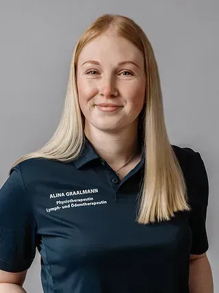 Blonde Frau mit einem sanften Lächeln, trägt ein dunkelblaues Poloshirt.