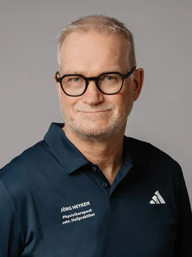 Mann mit Brille und blauem Adidas-Shirt, lächelnd; Studioporträt.