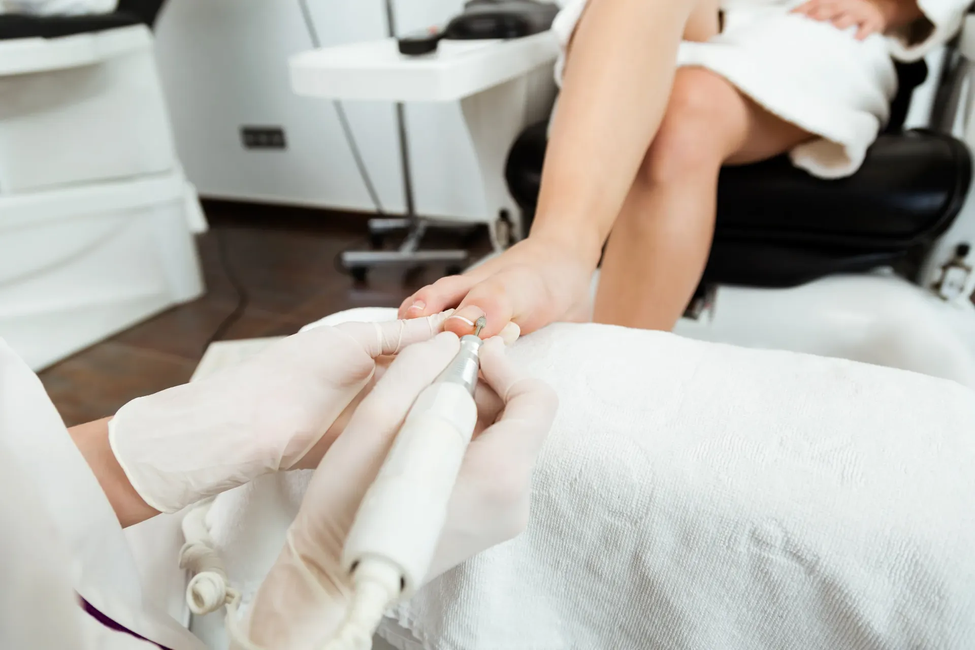 La manicurista lima las uñas de los pies de una clienta durante una pedicura en un salón.