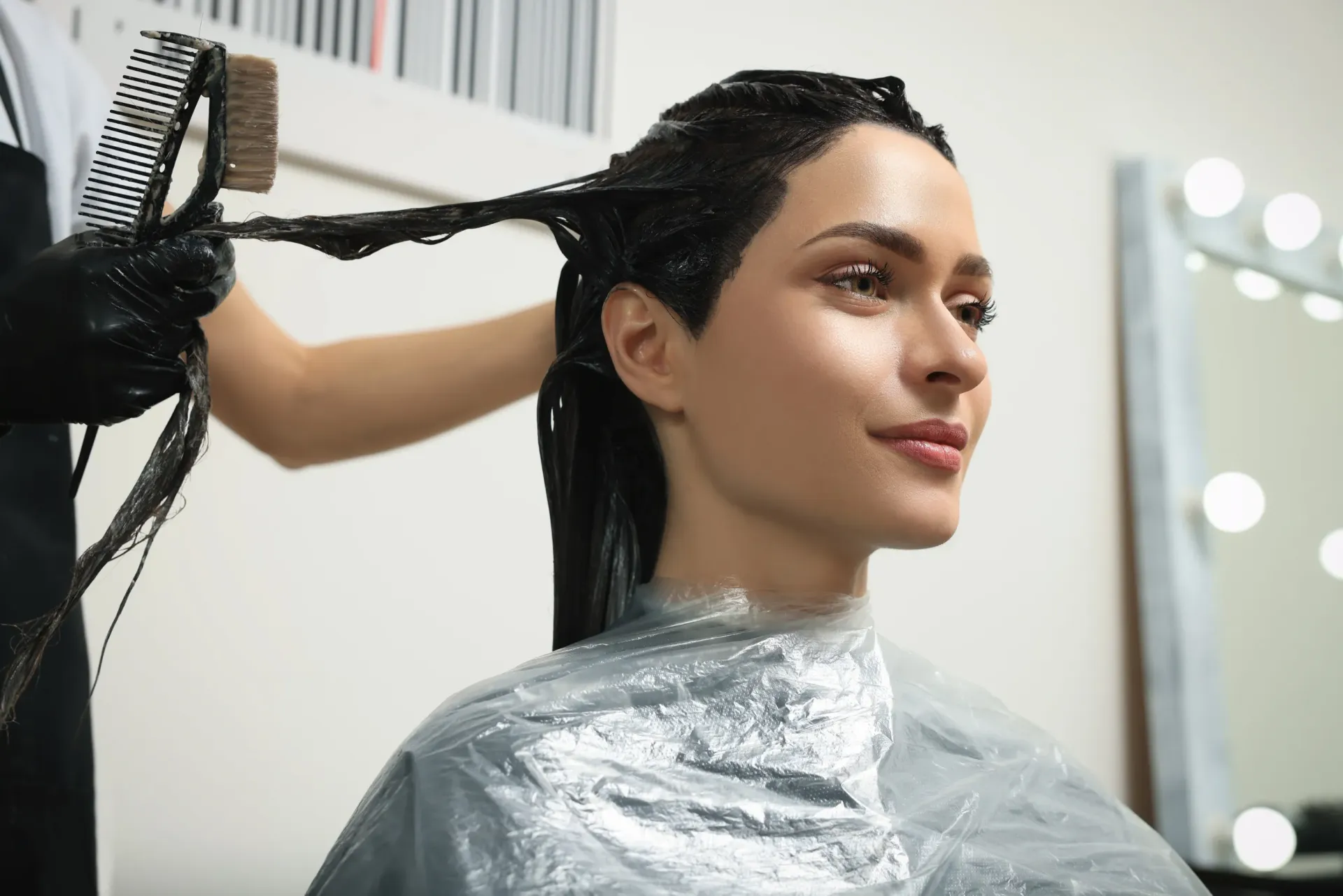Peluquero aplicando tinte para el cabello a una persona en un salón.
