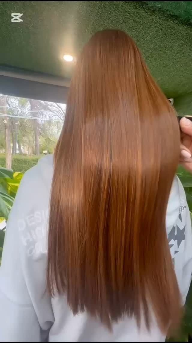Cabello largo, liso y castaño rojizo. Persona con sudadera blanca en un entorno de paredes verdes.