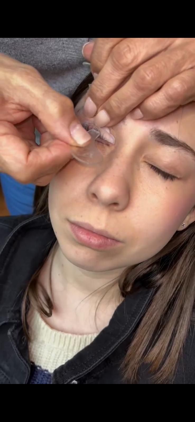 A una persona le están aplicando algo en la cara, cerca del ojo. Tiene los ojos cerrados.