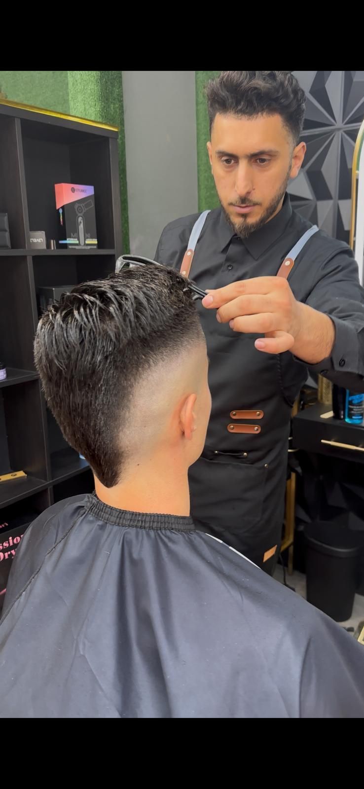 Peluquero cortando el cabello de un cliente, un degradado oscuro con un mohawk.