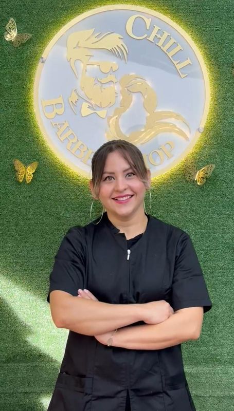 Mujer con los brazos cruzados sonriendo frente al cartel de