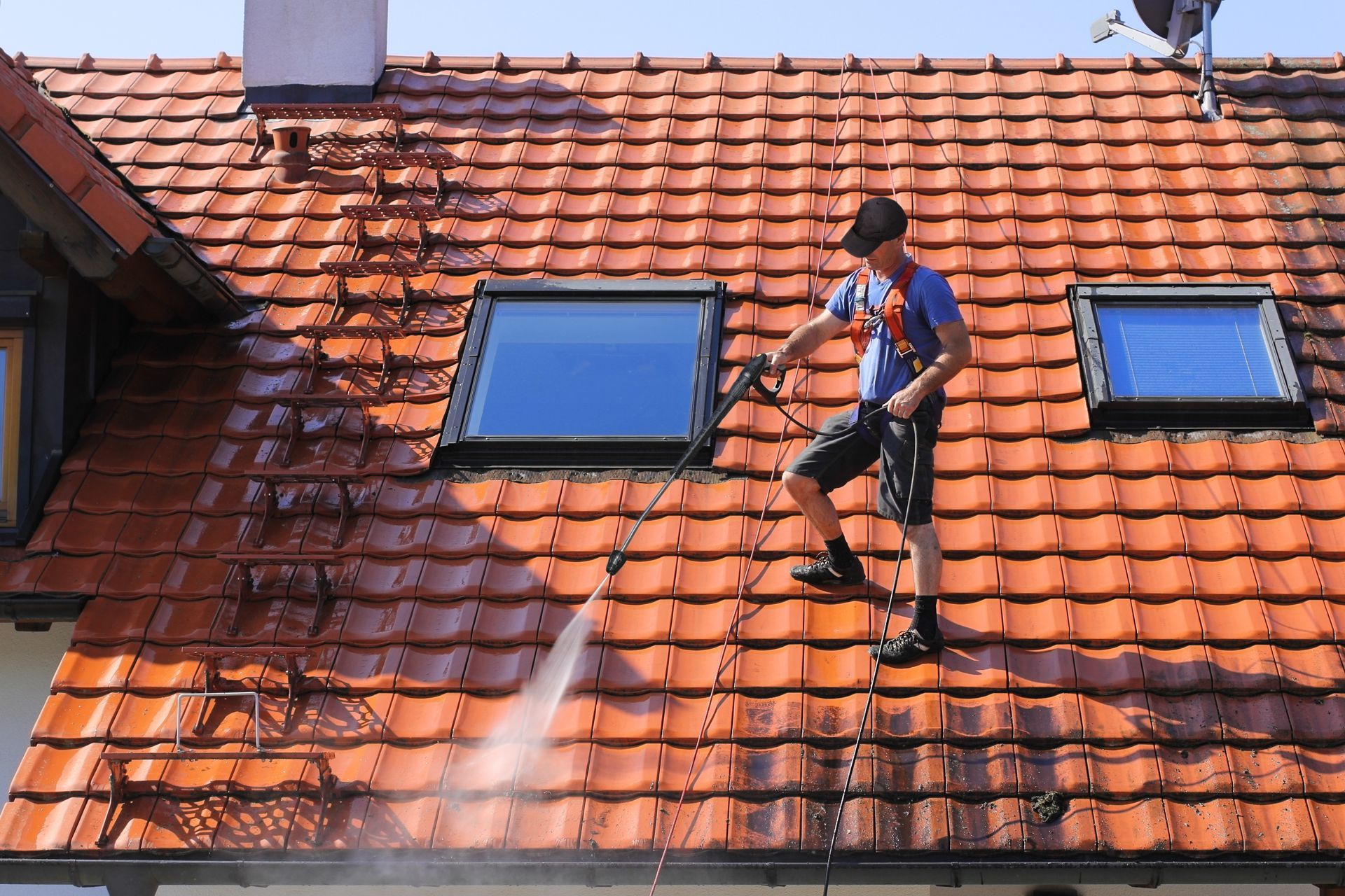 Homme en hanais procédant au nettoyage d'une toiture au Karcher
