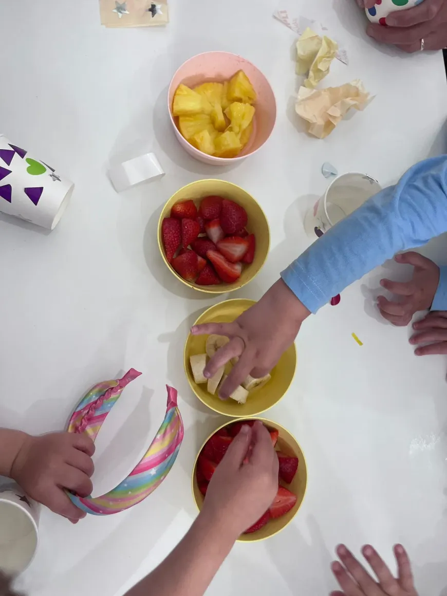 Manos de un niño pequeño cogiendo un trozo de plátano de un cuenco