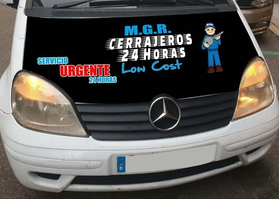 Una camioneta Mercedes blanca tiene una pegatina en el parabrisas que dice Mgr cerrajeros 24 horas bajo costo