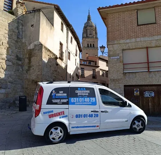 Una camioneta blanca está estacionada frente a un edificio de ladrillo.