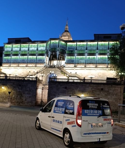 Una camioneta blanca está estacionada frente a un edificio que está iluminado por la noche.