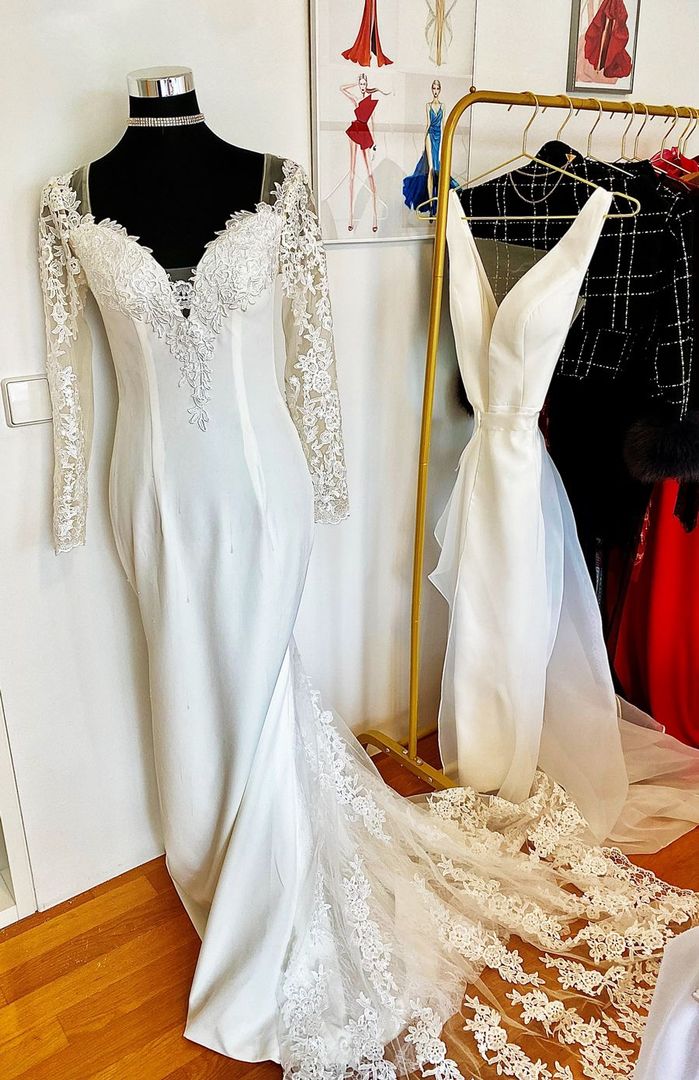 Ein weißes Brautkleid mit langen Ärmeln hängt auf einer Schaufensterpuppe in einem Raum.