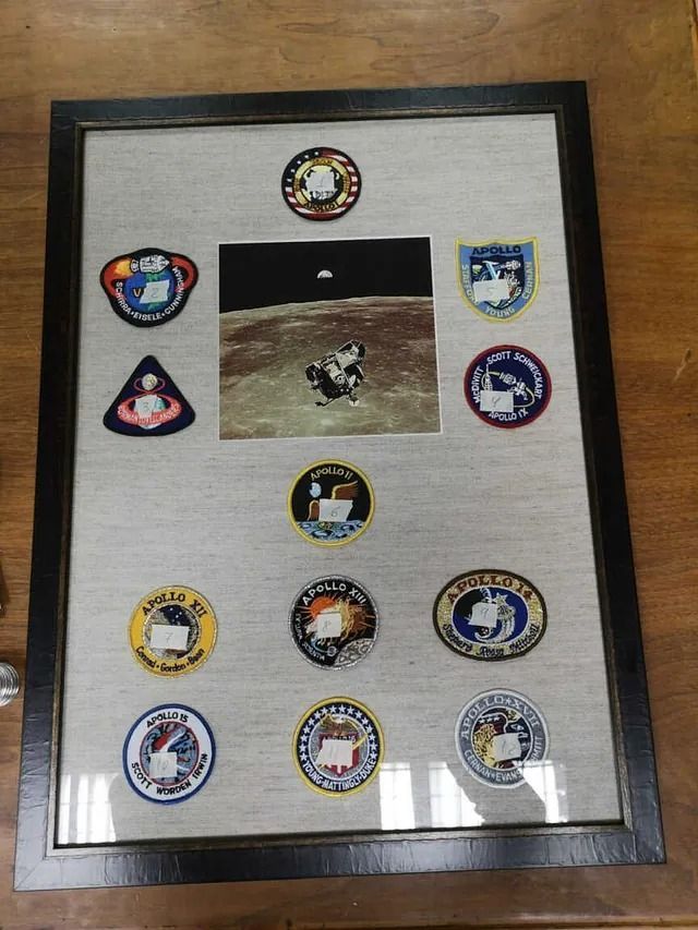 Una fotografía enmarcada de astronautas en la luna con insignias.
