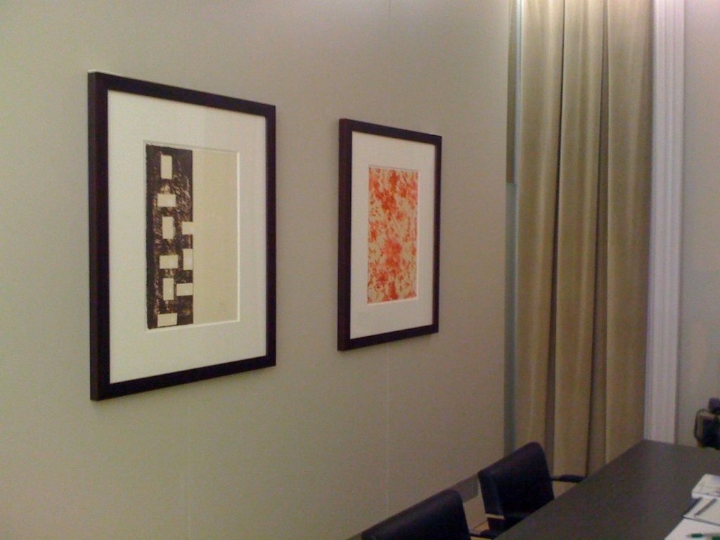 Dos cuadros enmarcados cuelgan en una pared junto a una mesa.
