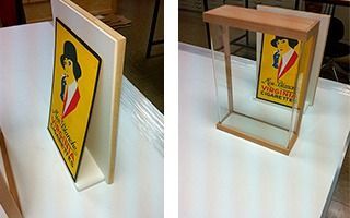 Un cartel amarillo con una mujer con sombrero está sobre una mesa blanca.