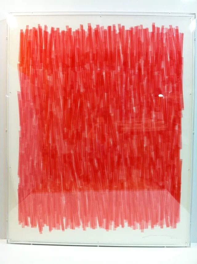 Un cuadro rojo y blanco en un marco transparente.