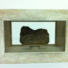 Un trozo de roca está en un marco de madera.