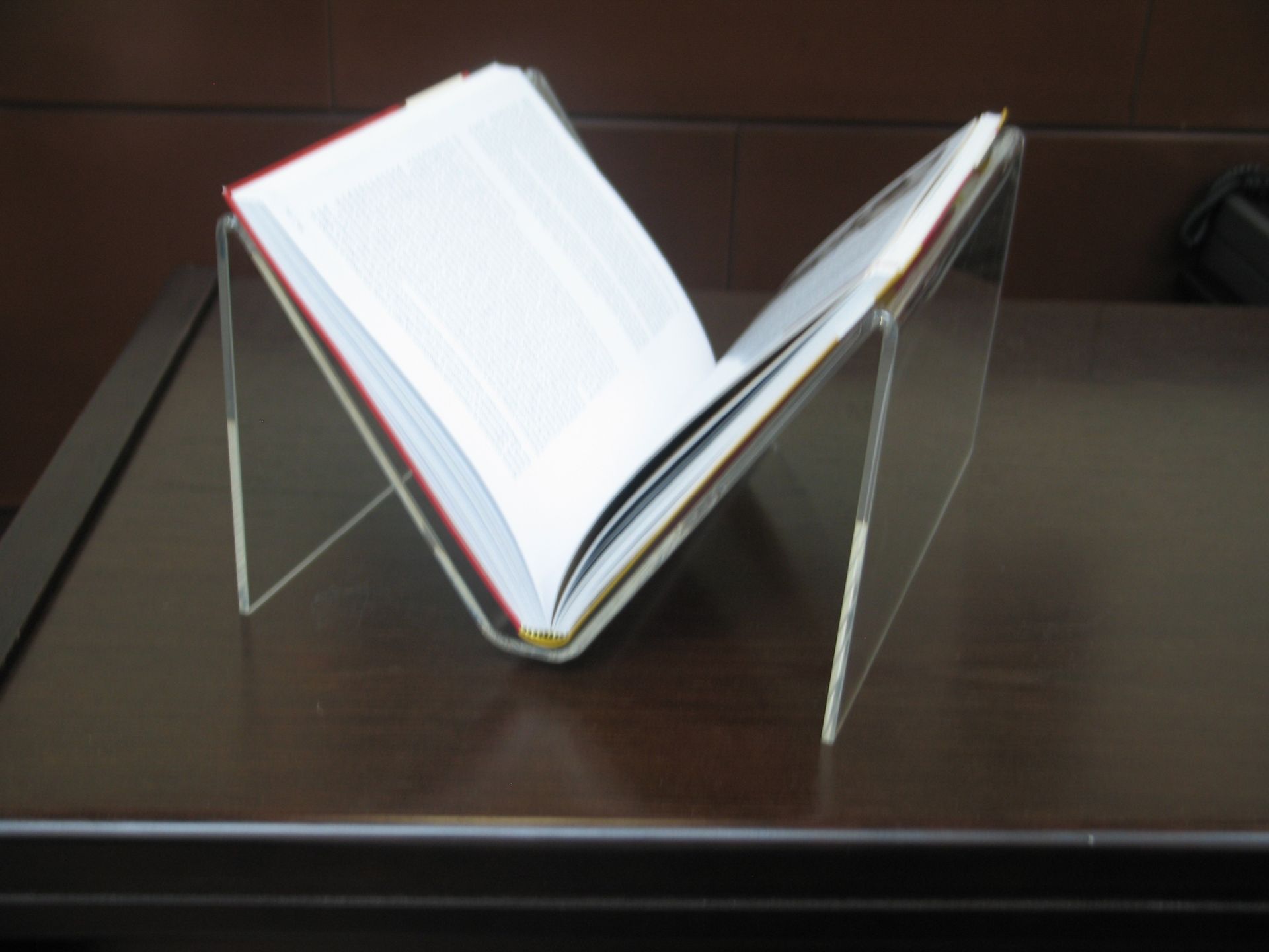 Un libro está sobre un soporte transparente sobre una mesa.