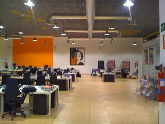 Una oficina grande con muchos escritorios y sillas.
