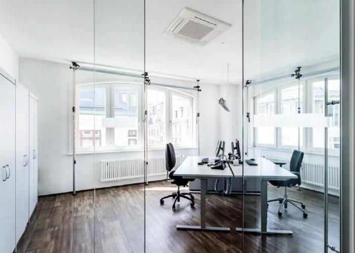 Ein Raum mit einer Glaswand und zwei Schreibtischen und Stühlen.