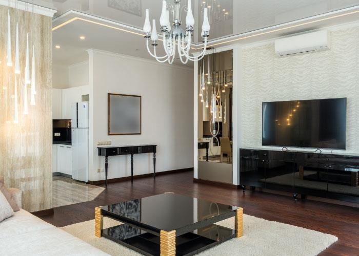 Ein Wohnzimmer mit Couchtisch, Fernseher und Kronleuchter.