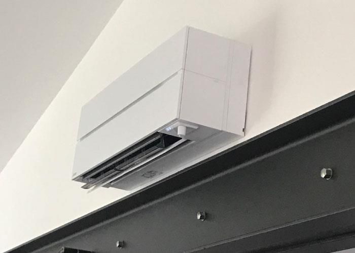 An einer weißen Wand hängt eine weiße Klimaanlage.