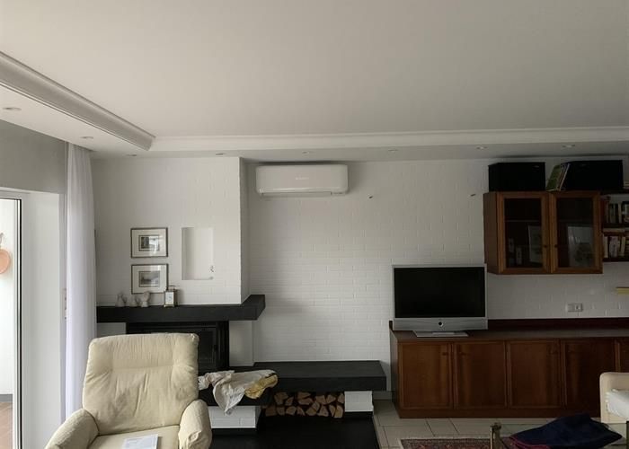 Ein Wohnzimmer mit Kamin, Sessel, Fernseher und Schränken.