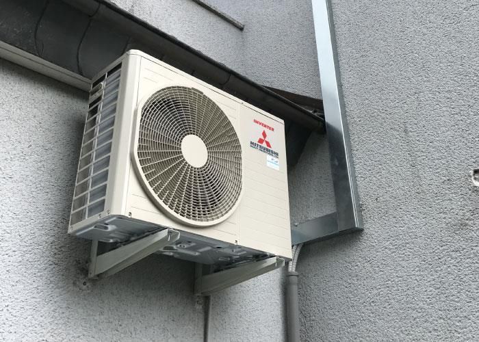 An der Seite eines Gebäudes ist eine weiße Klimaanlage montiert.