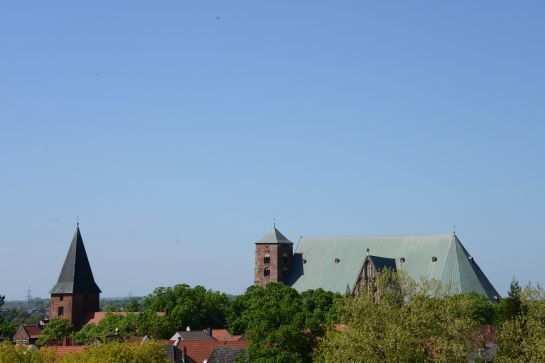 Ein großes Gebäude mit grünem Dach ist von Bäumen und einem blauen Himmel umgeben.