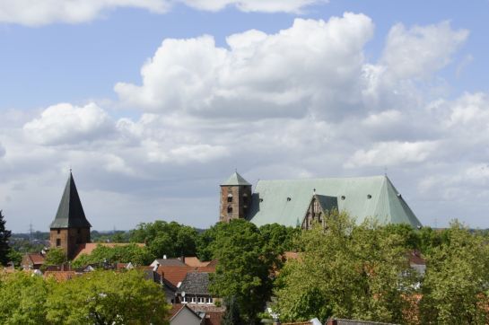 Eine Kirche mit grünem Dach ist von Bäumen und Häusern umgeben.