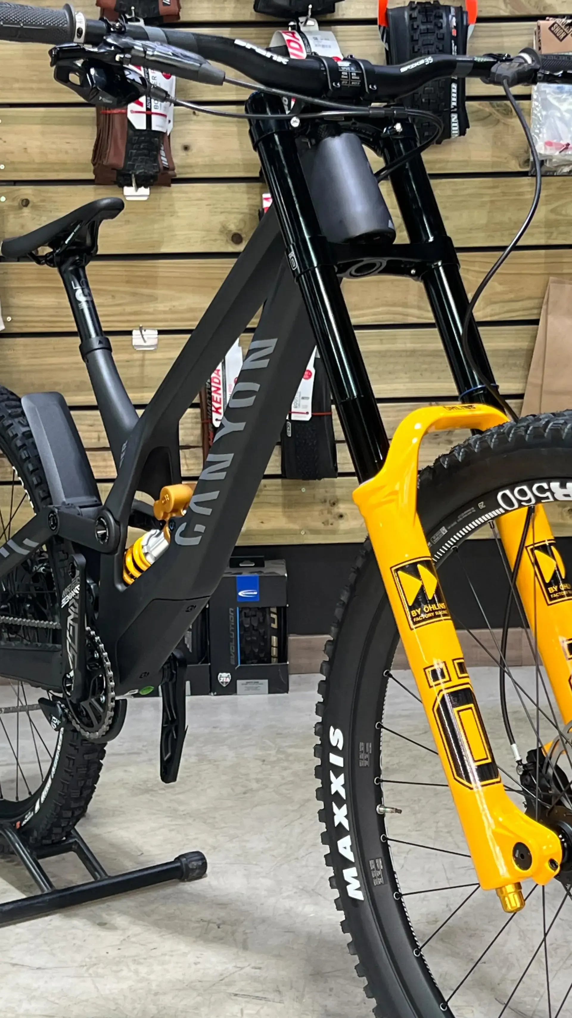 Una bicicleta de montaña negra con horquillas amarillas está estacionada en un garaje.