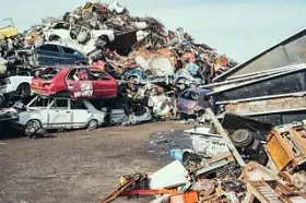 Una pila de coches y camiones están apilados uno encima del otro en un depósito de chatarra.