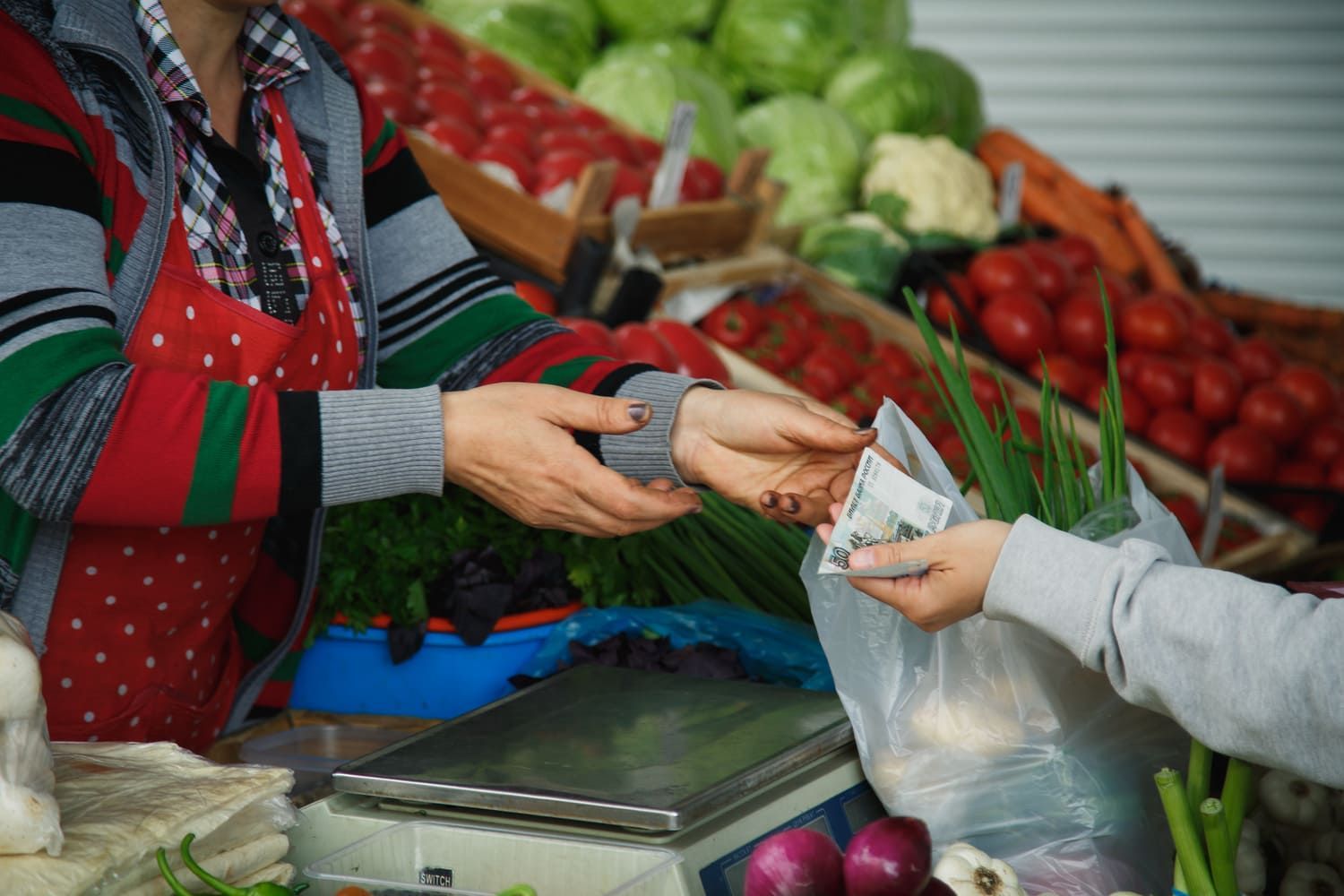 Una persona está pagando por verduras en un mercado.